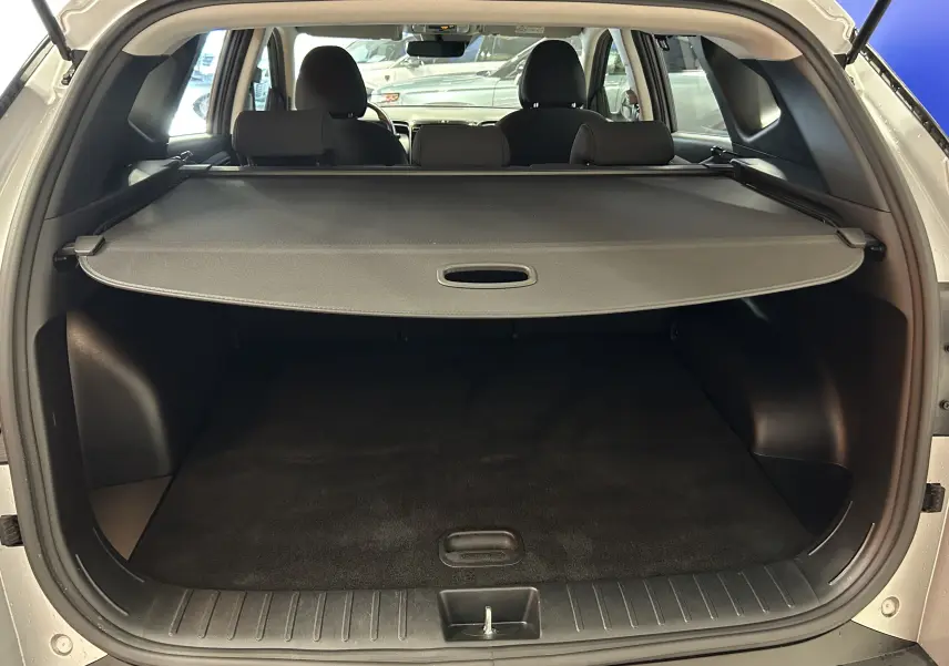 Coffre ouvert d’un Hyundai Tucson gris Shimmering Metal, vue arrière montrant la plage arrière et l’habitacle noir.