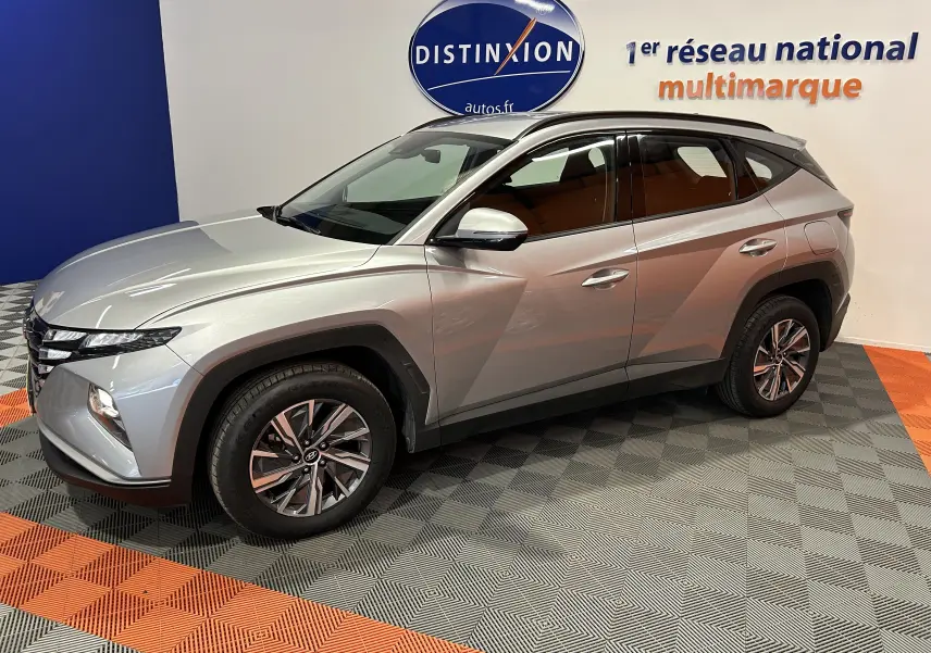 Hyundai Tucson hybride gris Shimmering Metal en 3/4 avant droit, roues alliage et détails noirs contrastants.