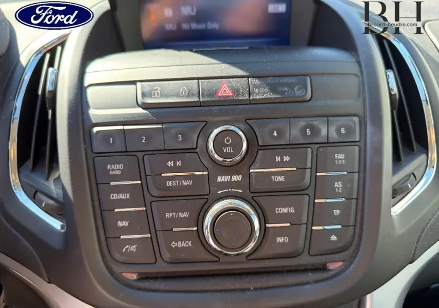 Console centrale noire vue de face avec commandes audio et navigation, affichage digital partiel, intérieur Ford.