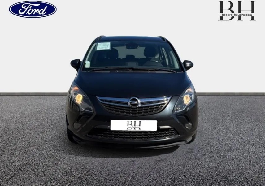 Vue avant d’un Opel Zafira Tourer gris métal avec phares allumés sur fond neutre.