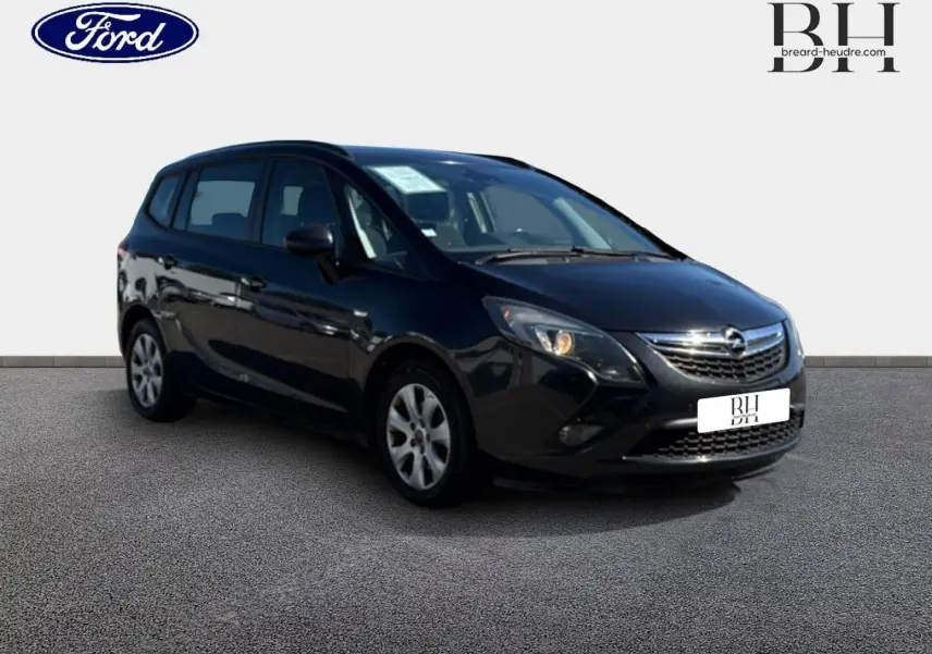 Opel Zafira Tourer gris métal vue 3/4 avant droit, avec calandre chromée et phares allumés.