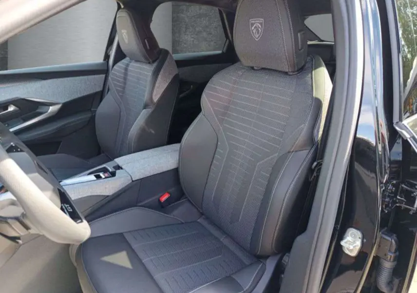 Intérieur du Peugeot 3008 2025 noir perla nera, vue côté gauche sur sièges avant avec logo GT brodé sur appuie-tête.