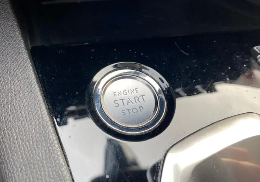 Bouton start/stop moteur en gros plan sur la console noire brillante du Peugeot 3008 gris platinium de 2021.