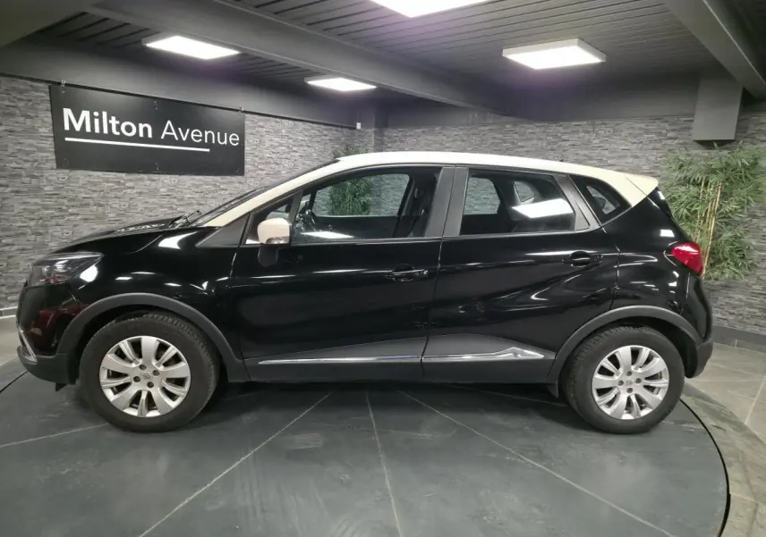 Profil côté gauche du Renault Captur noir avec toit et coques de rétroviseurs ivoire, jantes alliage 16 pouces visibles.