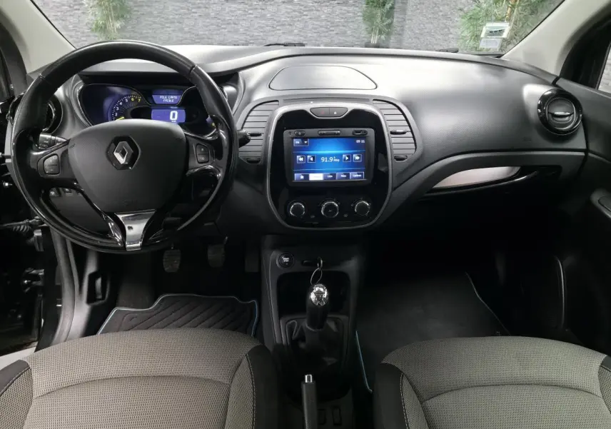 Intérieur noir et gris clair du Renault Captur 2014, vue frontale sur tableau de bord avec écran tactile et volant cuir.