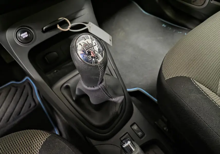 Gros plan sur le levier de vitesses manuel et siège avant gris clair ivoire du Renault Captur noir de 2014.