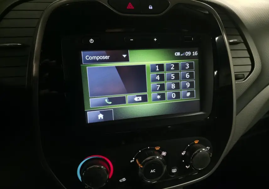 Vue rapprochée de l'écran tactile du système MédiaNav et des commandes de climatisation du Renault Captur noir 2014.