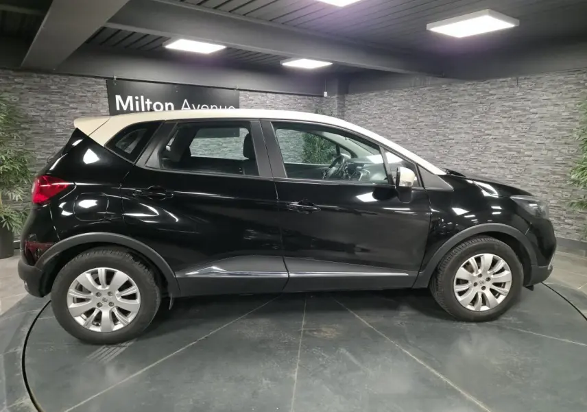 Renault Captur noir avec toit blanc en vue de profil côté gauche, dans un showroom intérieur.