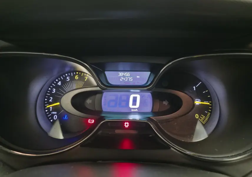 Tableau de bord numérique du Renault Captur noir 2014, affichant 0 km/h et compteurs éclairés en bleu et jaune.