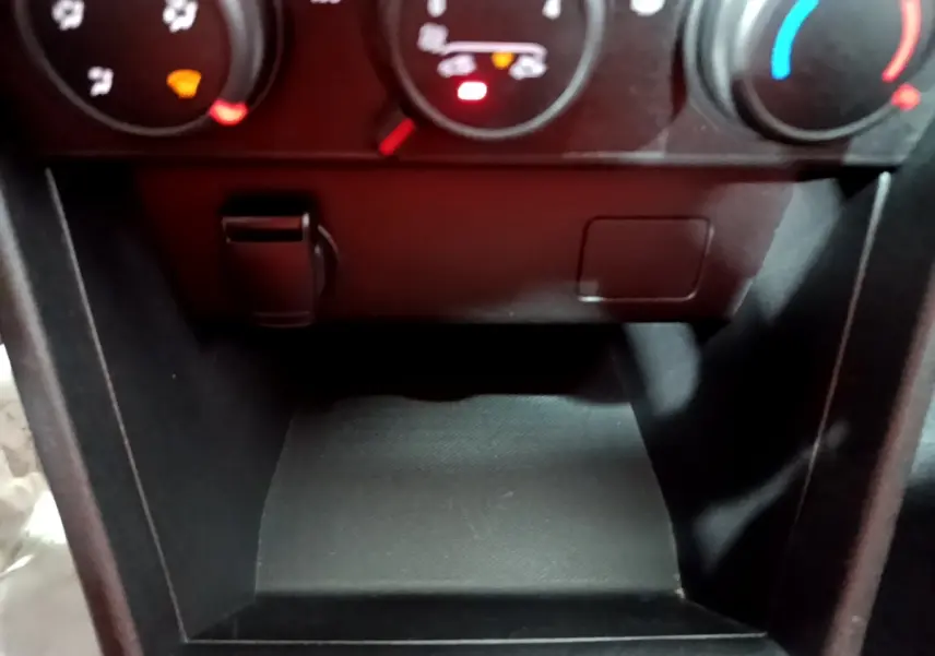 Gros plan sur la console centrale noire de la Dacia Sandero Confort TCe 90 2022, avec commandes de climatisation visibles.