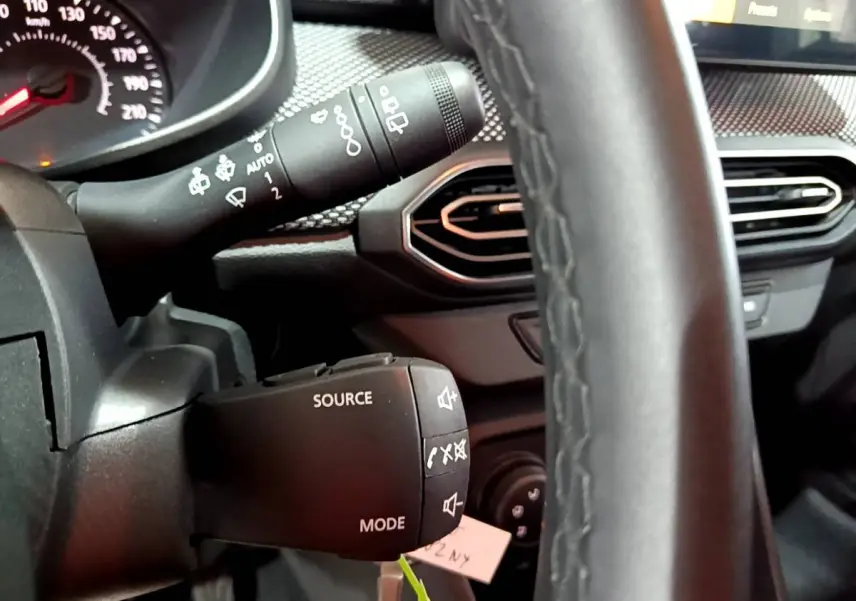 Gros plan sur le volant cuir synthétique et commandes multifonctions de la Dacia Sandero Confort TCe 90 2022.