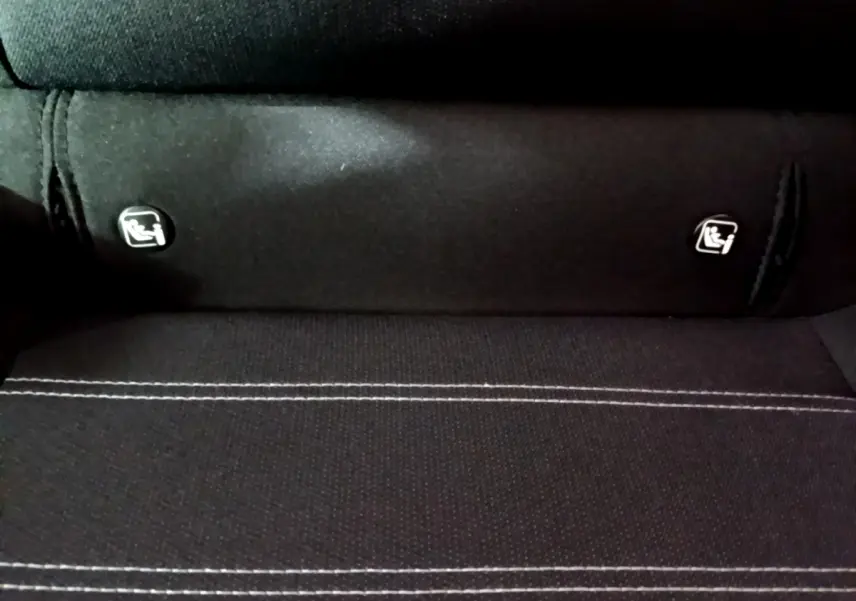 Gros plan sur la banquette arrière noire de la Dacia Sandero avec les logos de fixation Isofix visibles.