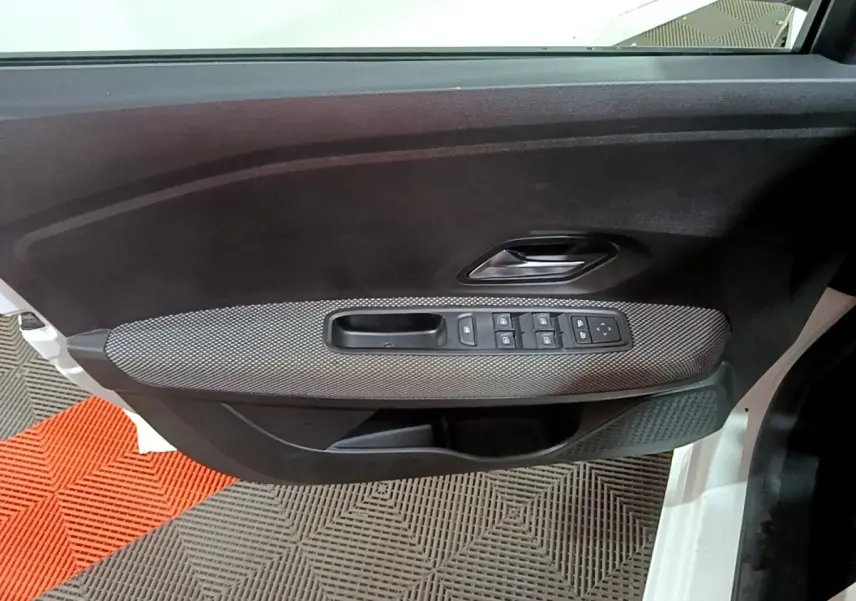 Vue intérieure côté gauche de la porte avant blanche de la Dacia Sandero avec commandes de vitres et poignée intégrée.