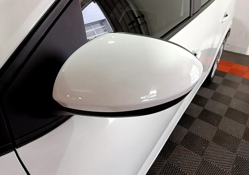 Gros plan sur le rétroviseur côté gauche blanc de la Dacia Sandero Confort TCe 90 -22B, vue partielle du véhicule.