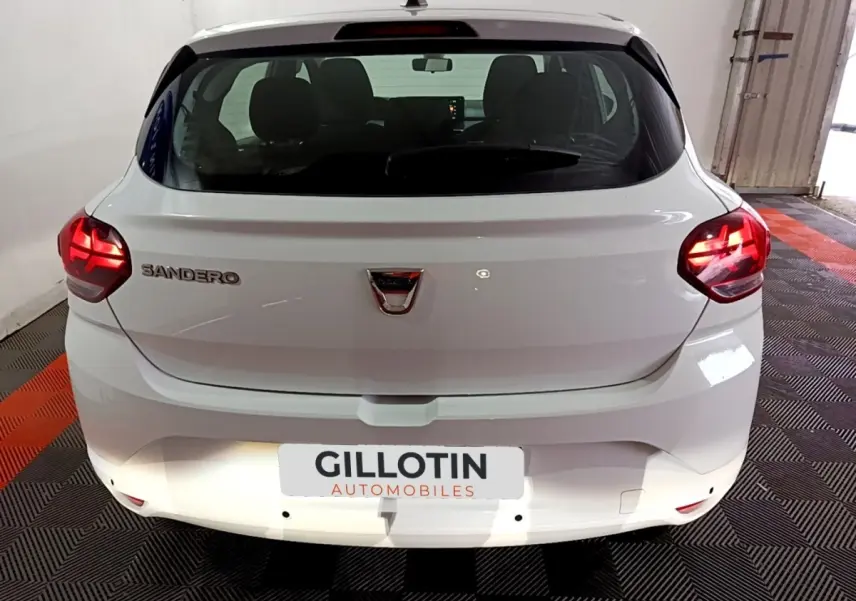 Vue arrière d'une Dacia Sandero blanche 2022 avec feux LED allumés dans un garage fermé.