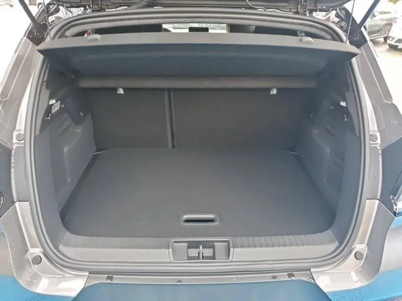 Vue arrière du coffre ouvert d'un Renault Captur 1.6 E-Tech gris Cassiopée, montrant un espace de chargement spacieux et propre.