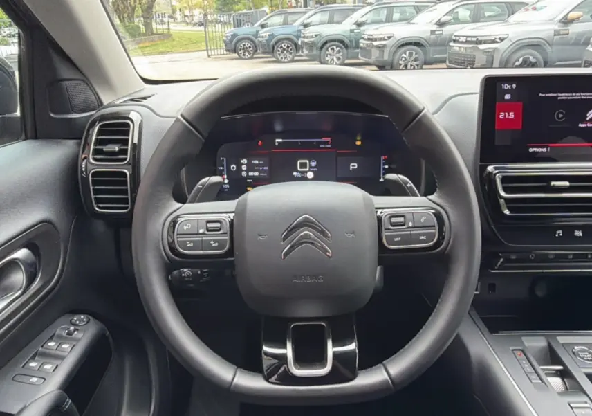 Vue intérieure centrée sur le volant cuir multifonctions du Citroën C5 Aircross Hybrid 2025 avec tableau de bord numérique et écran tactile.