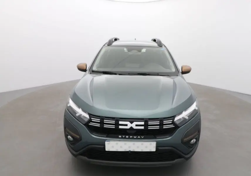 Vue frontale d'une Dacia Sandero Stepway 2025 vert cèdre avec détails bronze sur les rétroviseurs et calandre noire.