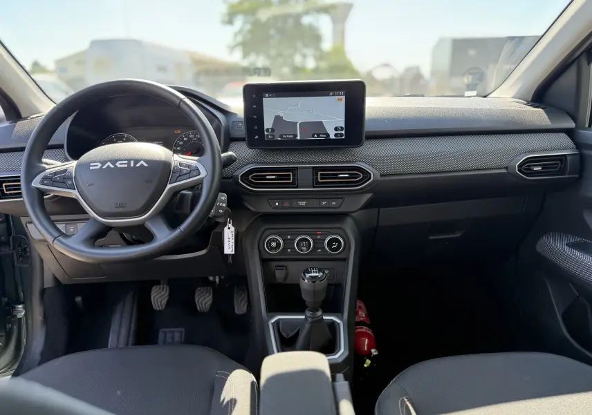 Vue intérieure avant du tableau de bord de la Dacia Sandero Stepway 2025 avec volant multifonction et écran tactile central.