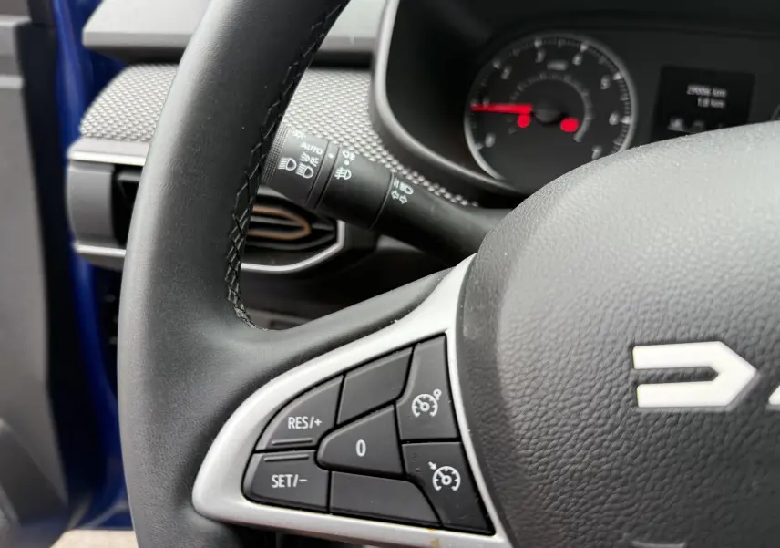 Gros plan sur le volant noir du Dacia Sandero Stepway 2025, montrant les commandes de régulateur de vitesse côté gauche.