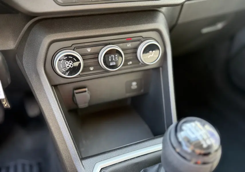 Gros plan sur la console centrale et la commande de climatisation de la Dacia Sandero Stepway TCE 90, intérieur noir.
