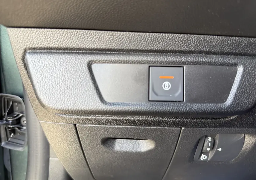 Gros plan sur le bouton de verrouillage centralisé sur la partie inférieure gauche du tableau de bord d’une Dacia Sandero Stepway Vert Cèdre.