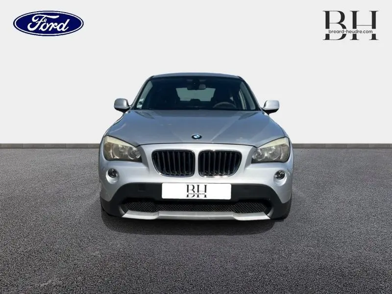 Vue frontale d'un BMW X1 gris métal de 2011 avec calandre double haricot et phares larges.