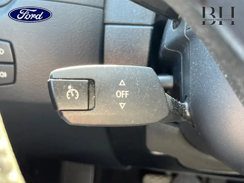 Le véhicule visible sur l'image est un Ford, or la description demandée concerne un BMW X1. L'image montre un détail intérieur d'un levier de commande de régulateur de vitesse sur un volant, sans indication claire du modèle BMW X