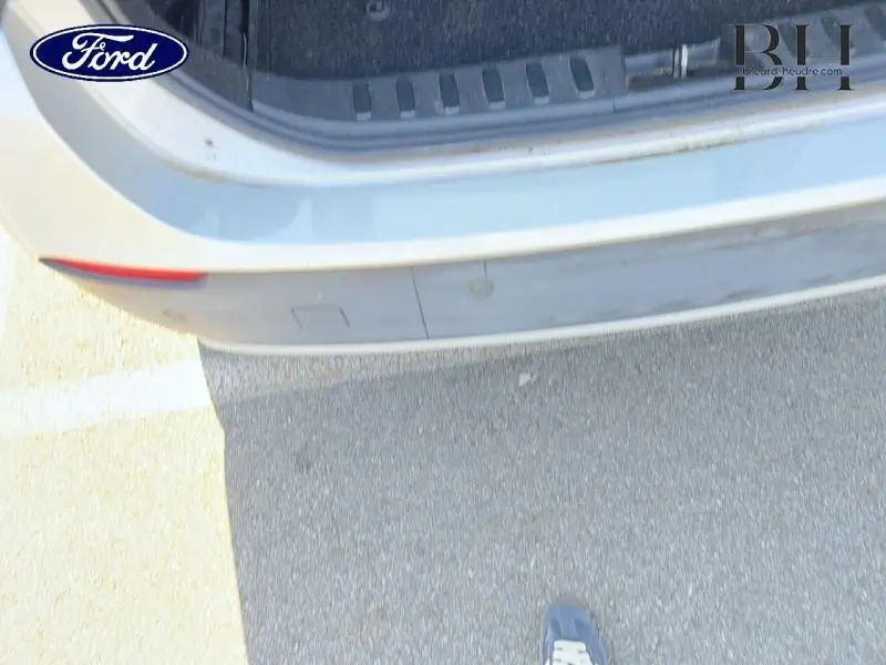Vue rapprochée du pare-chocs arrière gris d'un BMW X1 sDrive18dA 2011 avec capteurs de stationnement visibles.