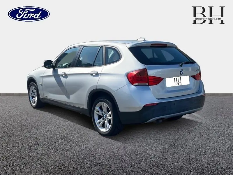 Vue 3/4 arrière droite d'un BMW X1 gris métallisé avec jantes alu 17 pouces sur fond neutre.