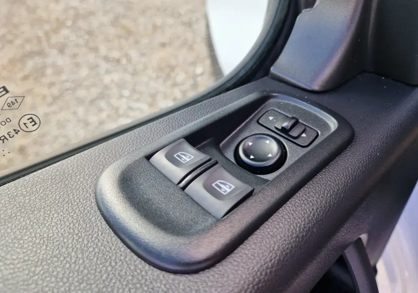 Gros plan sur les commandes électriques des vitres et des rétroviseurs côté conducteur du Renault Master blanc 2024.