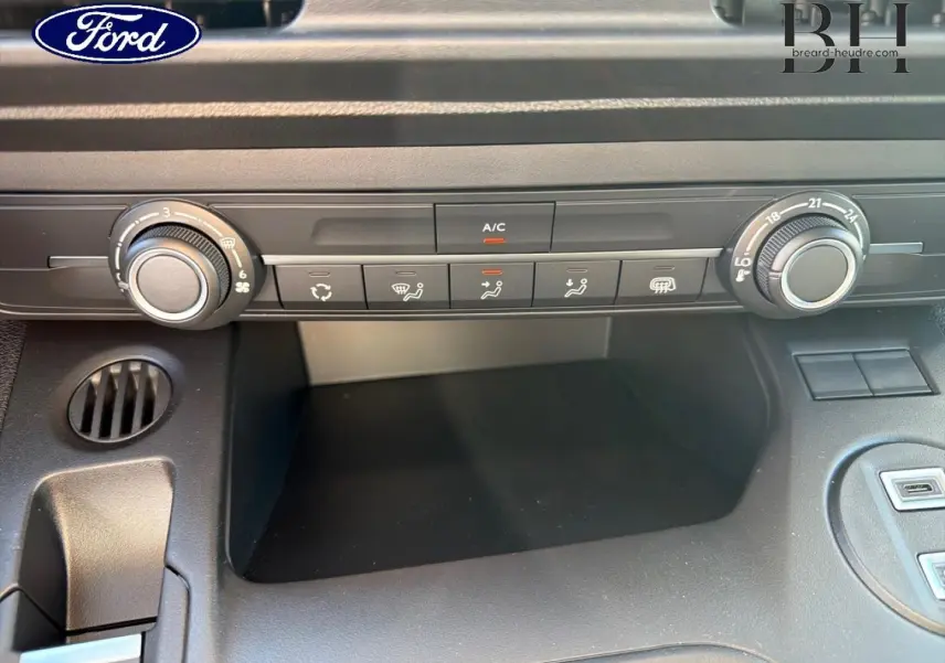 Tableau de bord en gros plan du Peugeot Partner blanc, montrant les commandes de climatisation et ventilation.