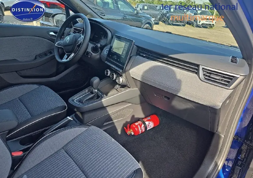 Vue intérieure côté passager d'une Renault Clio V bleu iron, avec tableau de bord moderne et sièges gris tissu.