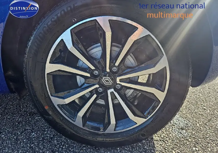 Gros plan sur la jante alu noire et argentée d'une Renault Clio V Bleu Iron, avec logo Renault au centre.