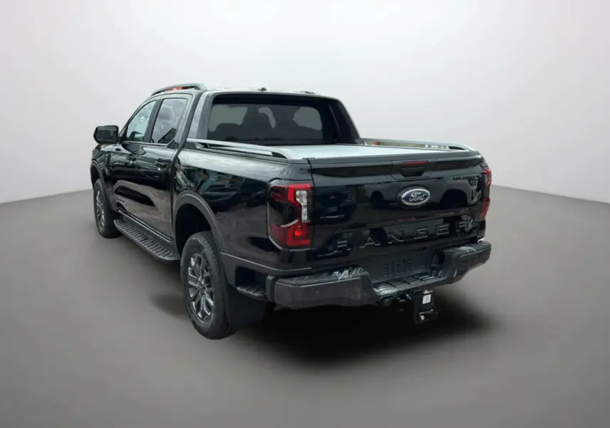 Ford Ranger 2025 noir agate vu en 3/4 arrière droit, avec benne couverte et attelage visible.