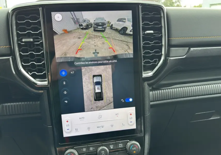 Écran central du Ford Ranger 2025 Wildtrak Plus montrant la caméra de recul avec vue aérienne, tableau de bord noir avec surpiqûres jaunes.