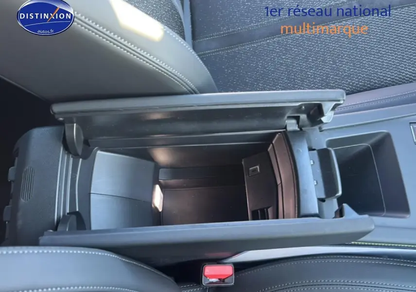Vue plongeante sur l'accoudoir central noir ouvert du Peugeot 408 Hybrid 145 GT, montrant le rangement intérieur.