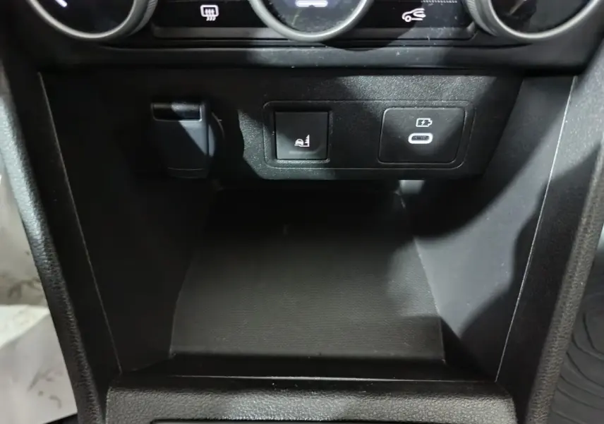 Gros plan sur la console centrale noire de la Dacia Sandero 2024 avec prise USB-C et bouton de siège chauffant.