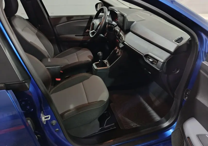 Vue intérieure côté conducteur de la Dacia Sandero Extreme+ bleu 2024, avec sièges tissu bicolore et volant multifonctions cuir synthétique.