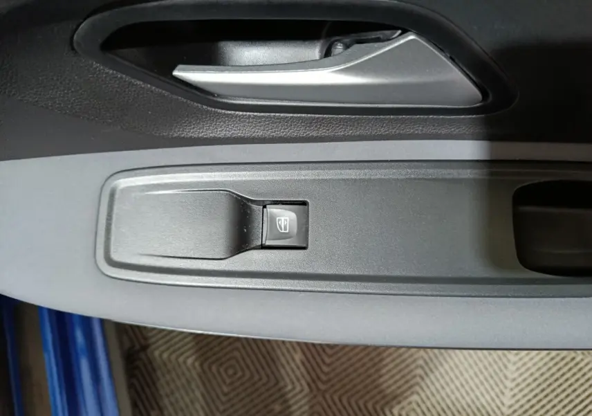 Gros plan sur la commande de lève-vitre côté conducteur de la Dacia Sandero Extreme+ TCe 110 bleu 2024.