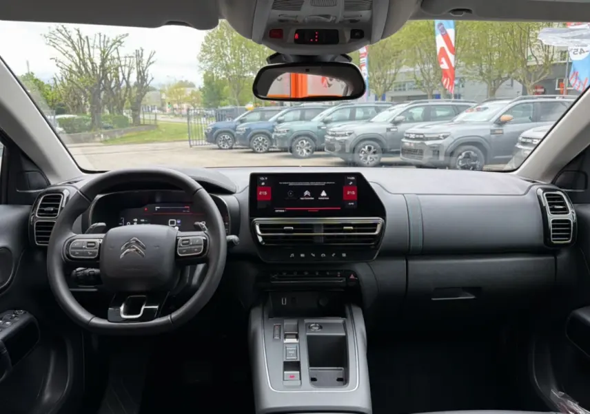 Vue intérieure frontale du tableau de bord du Citroën C5 Aircross Hybrid gris platinium avec écran tactile et volant multifonctions.