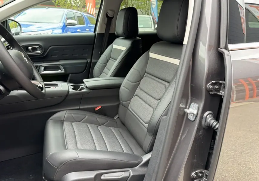Vue intérieure côté conducteur du Citroën C5 Aircross gris platinium, mettant en valeur le siège avant en cuir et tissu avec accoudoir central.