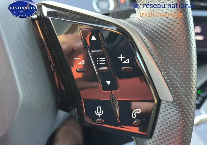 Gros plan sur les commandes multifonctions noires du volant cuir perforé côté gauche du Peugeot 3008 gris 2025.