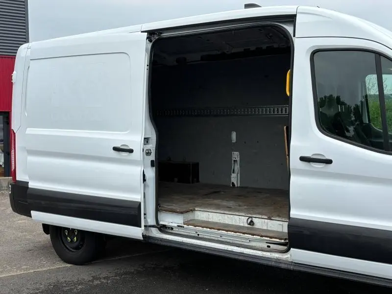 Vue latérale droite d'un Ford Transit Fourgon blanc Glacier avec porte coulissante ouverte dévoilant l'espace de chargement vide.