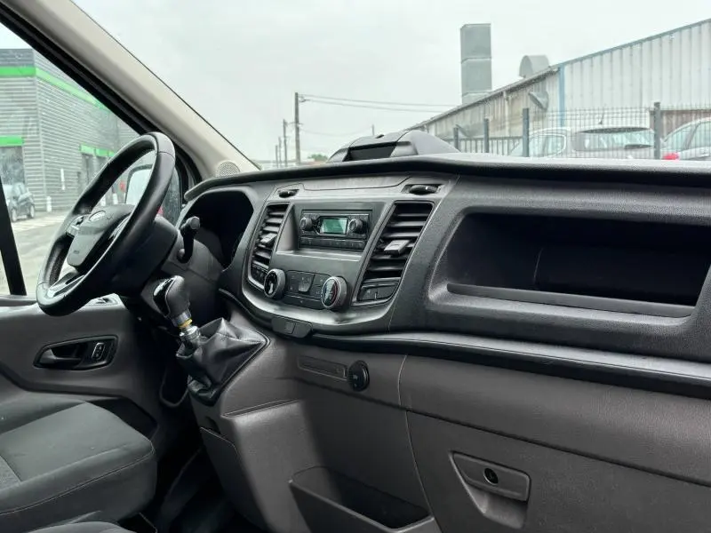 Vue intérieure côté conducteur du Ford Transit Fourgon blanc glacier 2022, tableau de bord et volant multifonction visibles.