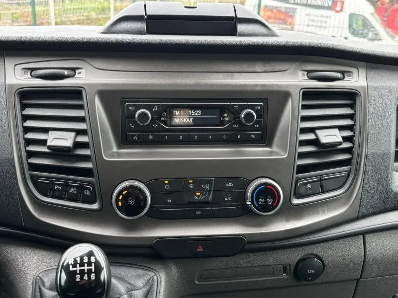 Tableau de bord du Ford Transit Fourgon blanc Glacier 2022, vue frontale centrée sur la console et la boîte manuelle