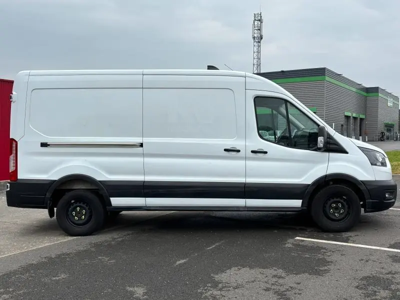 Ford Transit Fourgon blanc glacier vu de profil côté gauche, avec porte latérale coulissante et roues noires simples.