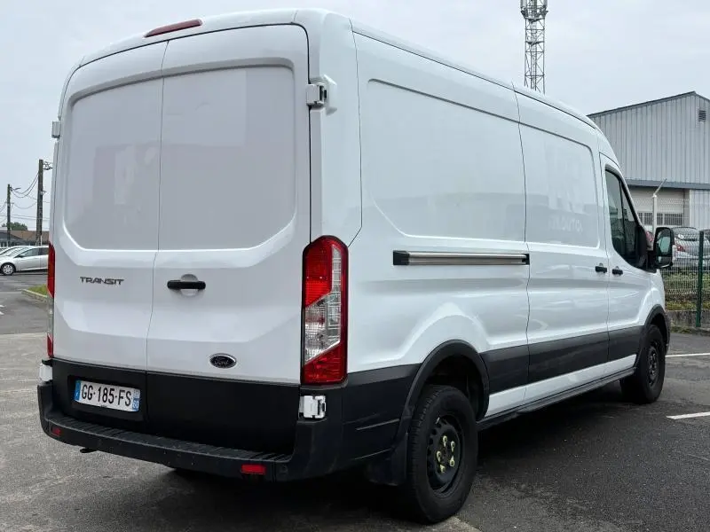 Fourgon Ford Transit blanc glacier vu en 3/4 arrière droit, avec portes arrière battantes et porte latérale coulissante.