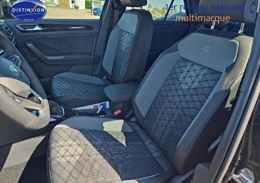 Intérieur Volkswagen T-Roc 2025, vue côté gauche sur sièges tissu noir et gris avec logo R-Line brodé.
