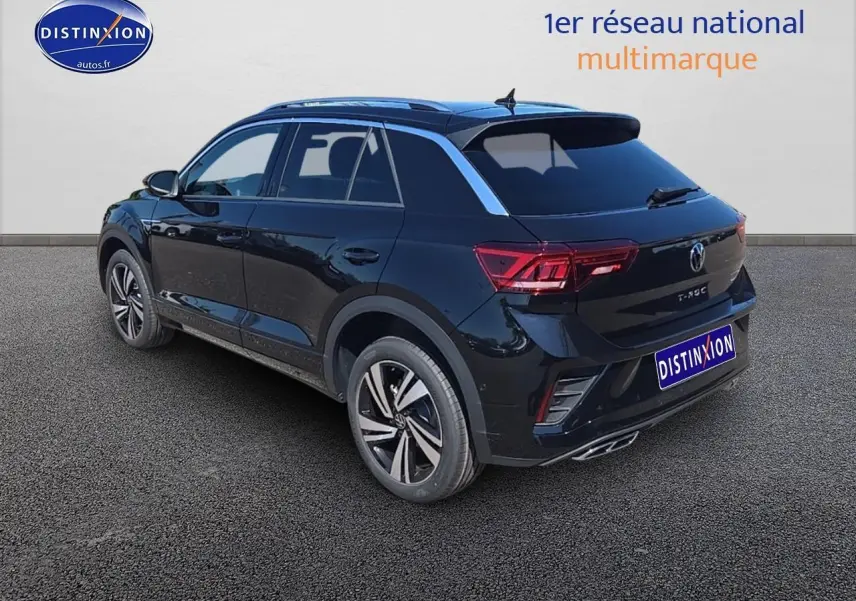 Volkswagen T-Roc noir perle en 3/4 arrière droit avec jantes alliage et barres de toit argentées visibles.